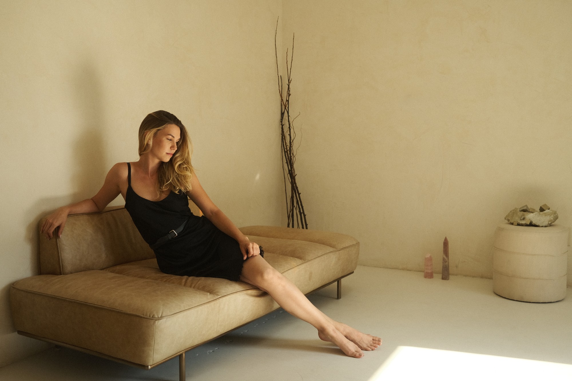 Brittany in studio, leather sofa, crystals, warm light
