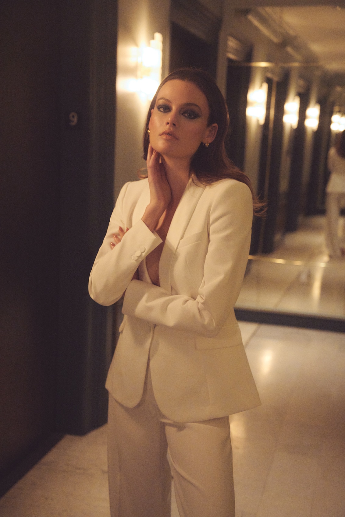 Hotel hallway editorial, white suit, amber lighting, mirrors