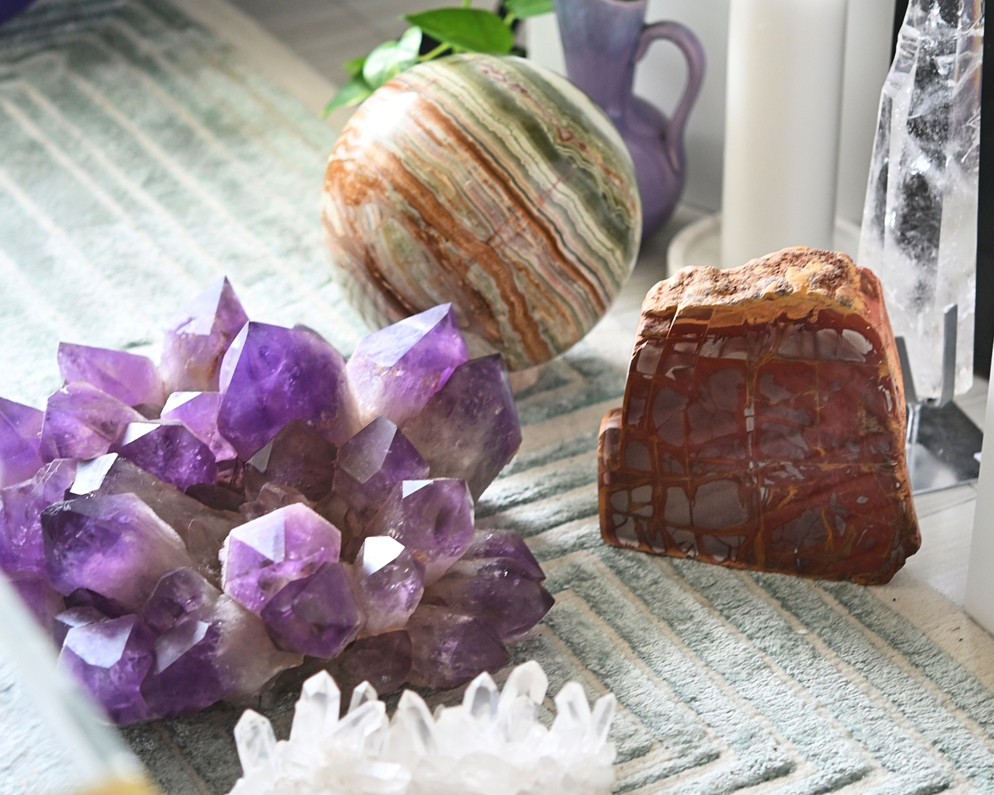 Mineral collection on shelf: amethyst cluster, onyx sphere, jasper slab