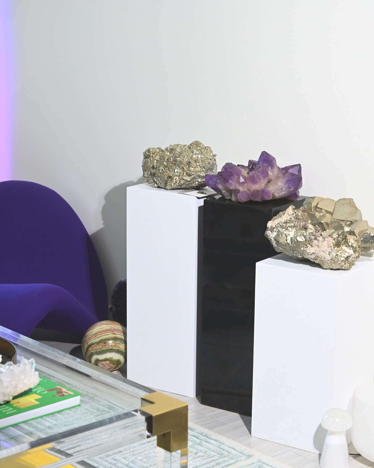 Gallery display: pyrite, amethyst, onyx on pedestals with Womb chair