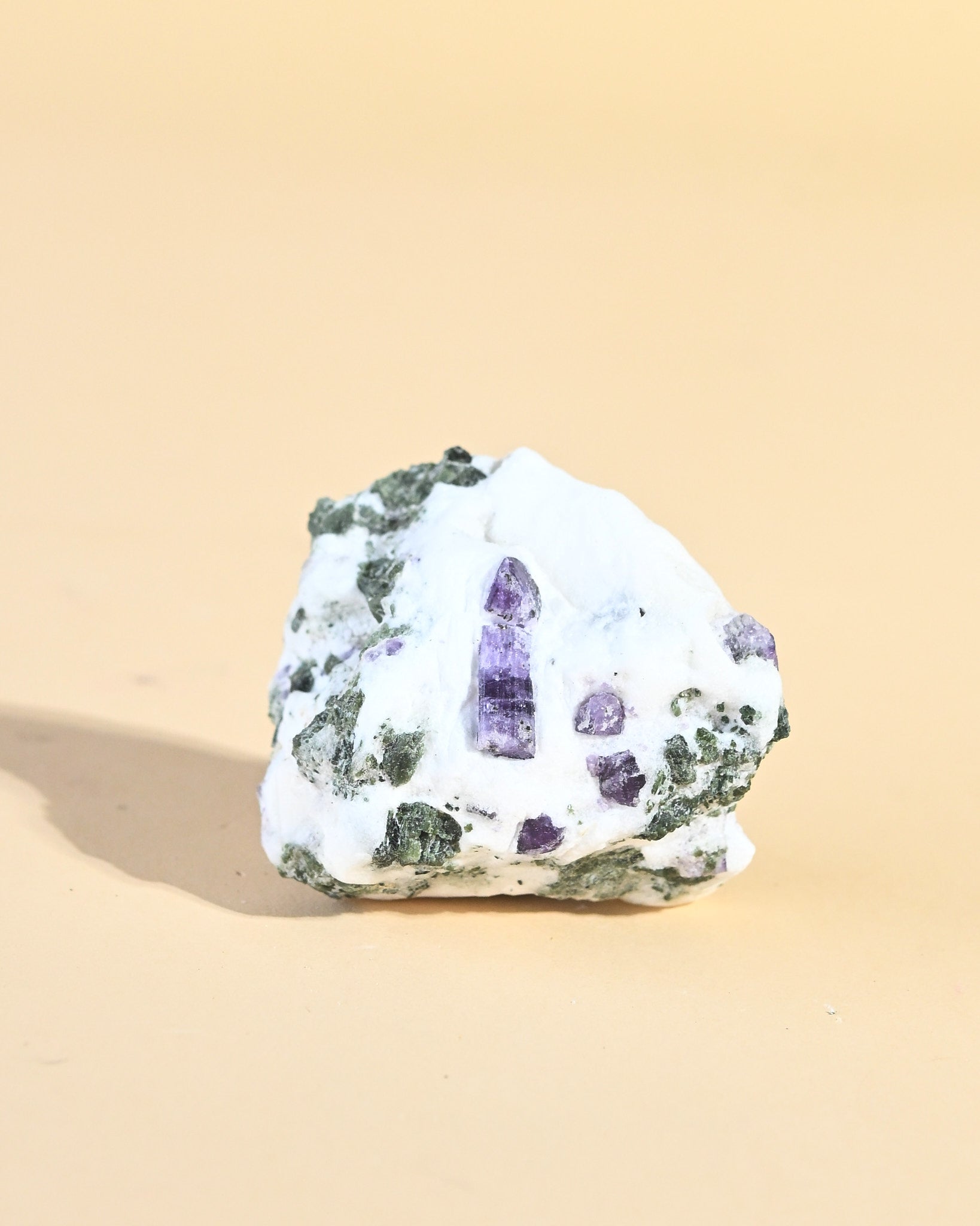 Scapolite in calcite matrix, purple points emerging from white stone
