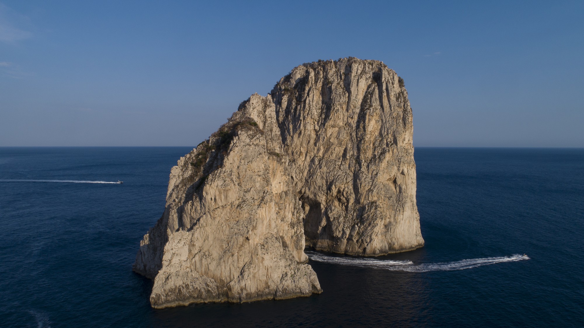 Faraglioni rocks aerial drone, deep blue Mediterranean, Capri coastline from above