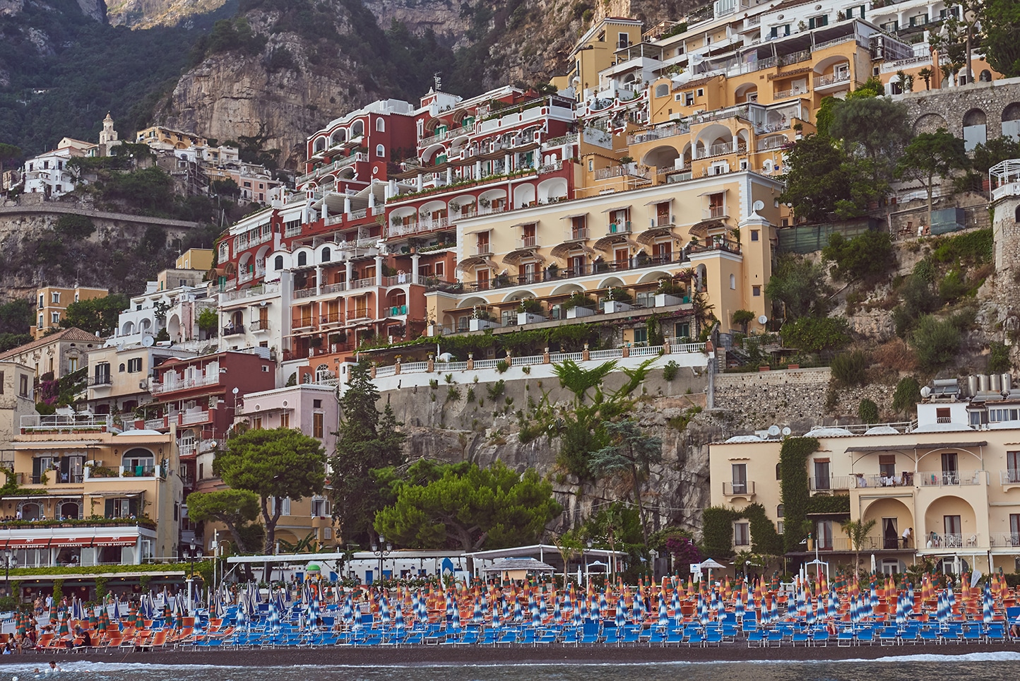Positano from the water, pastel facades, beach umbrellas