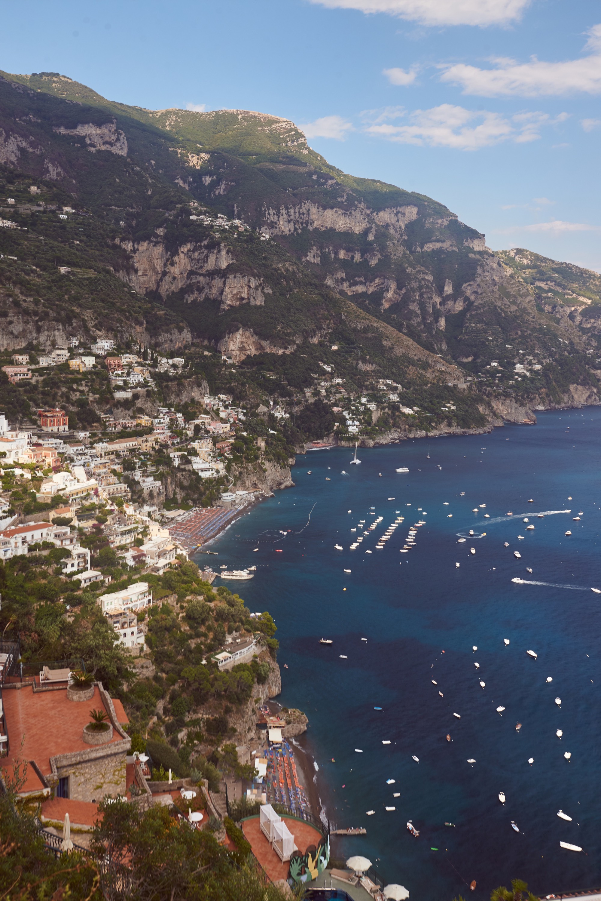 Positano from above, boats dotting the bay, terraced hotels cascading down