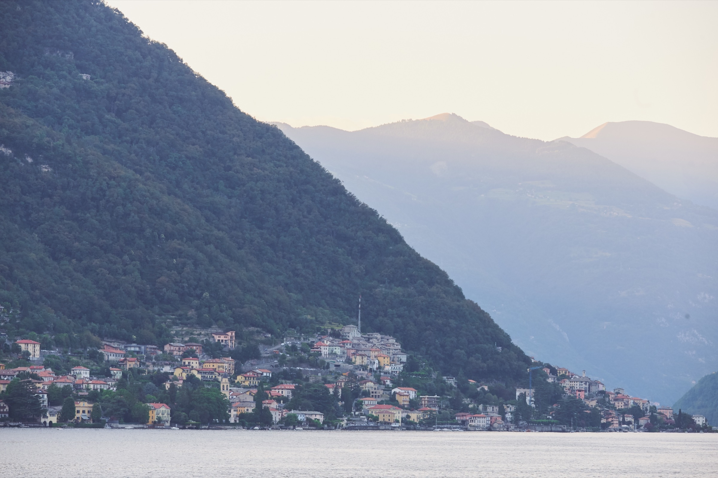 Lake Como village at dusk, colorful houses on hillside, misty mountains
