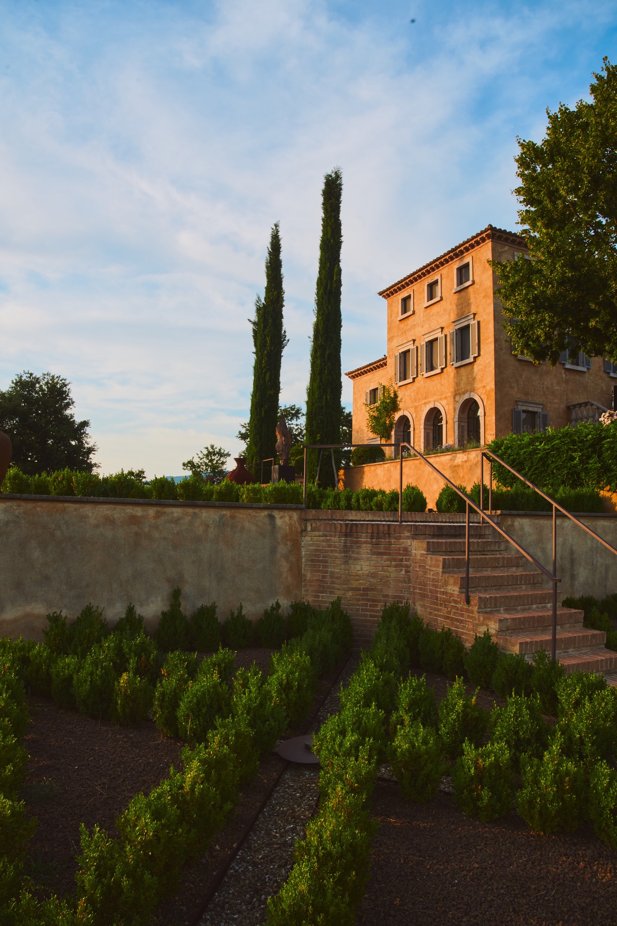 Tuscan villa with cypress trees at golden hour, manicured garden, warm stone