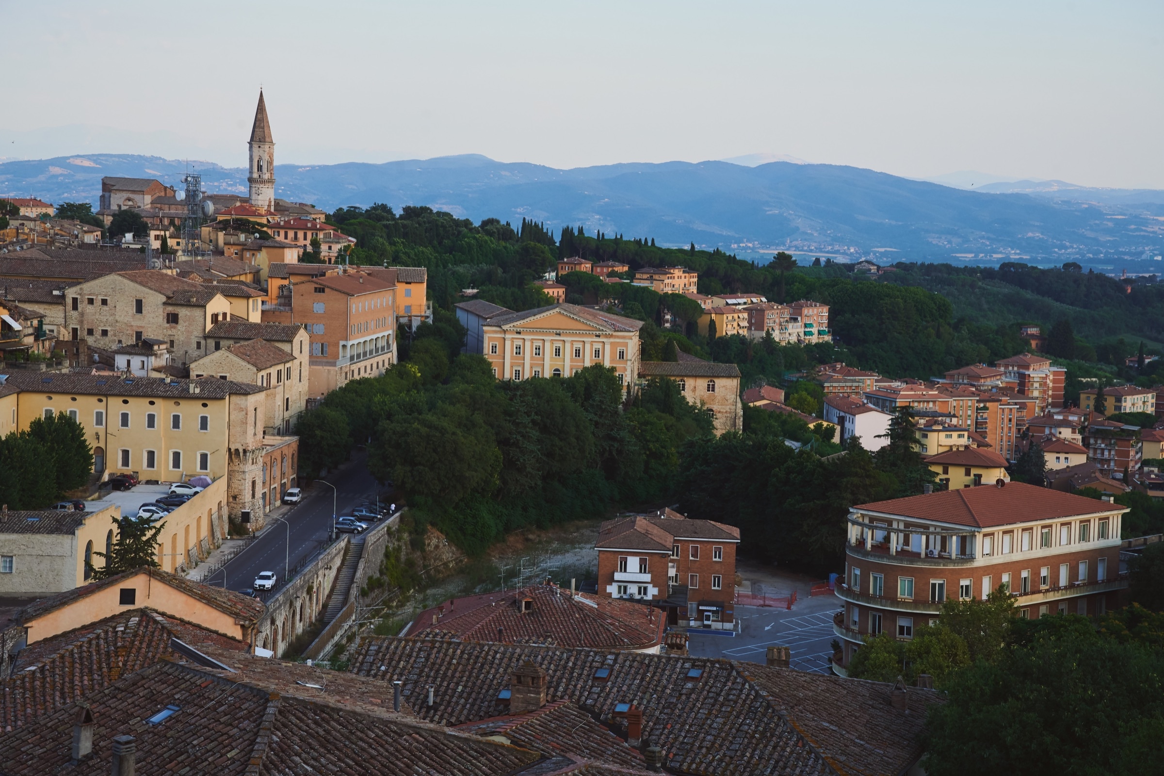 Perugia rooftop view at dusk, church spire silhouetted, Umbrian hills