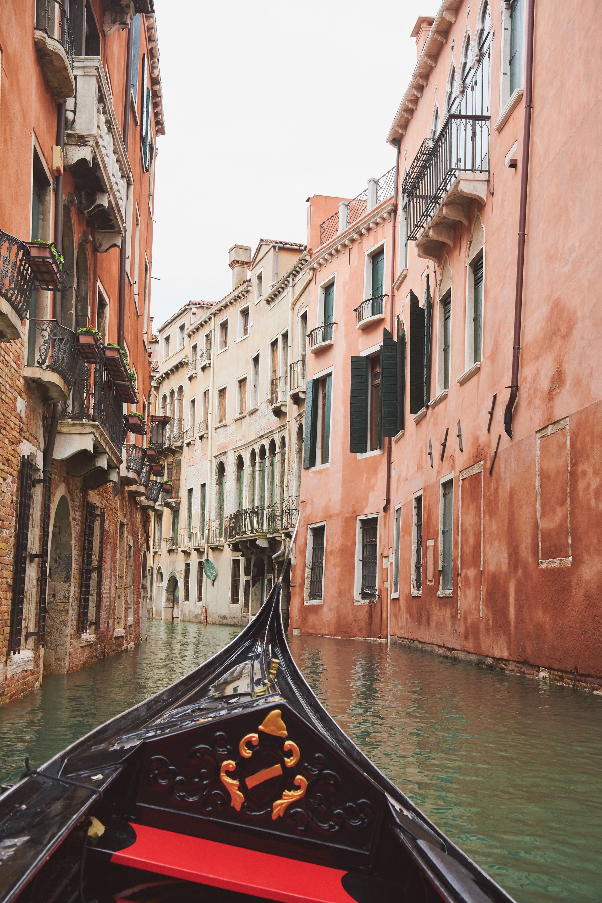 Venice gondola POV through narrow canal, pink and terracotta palazzi