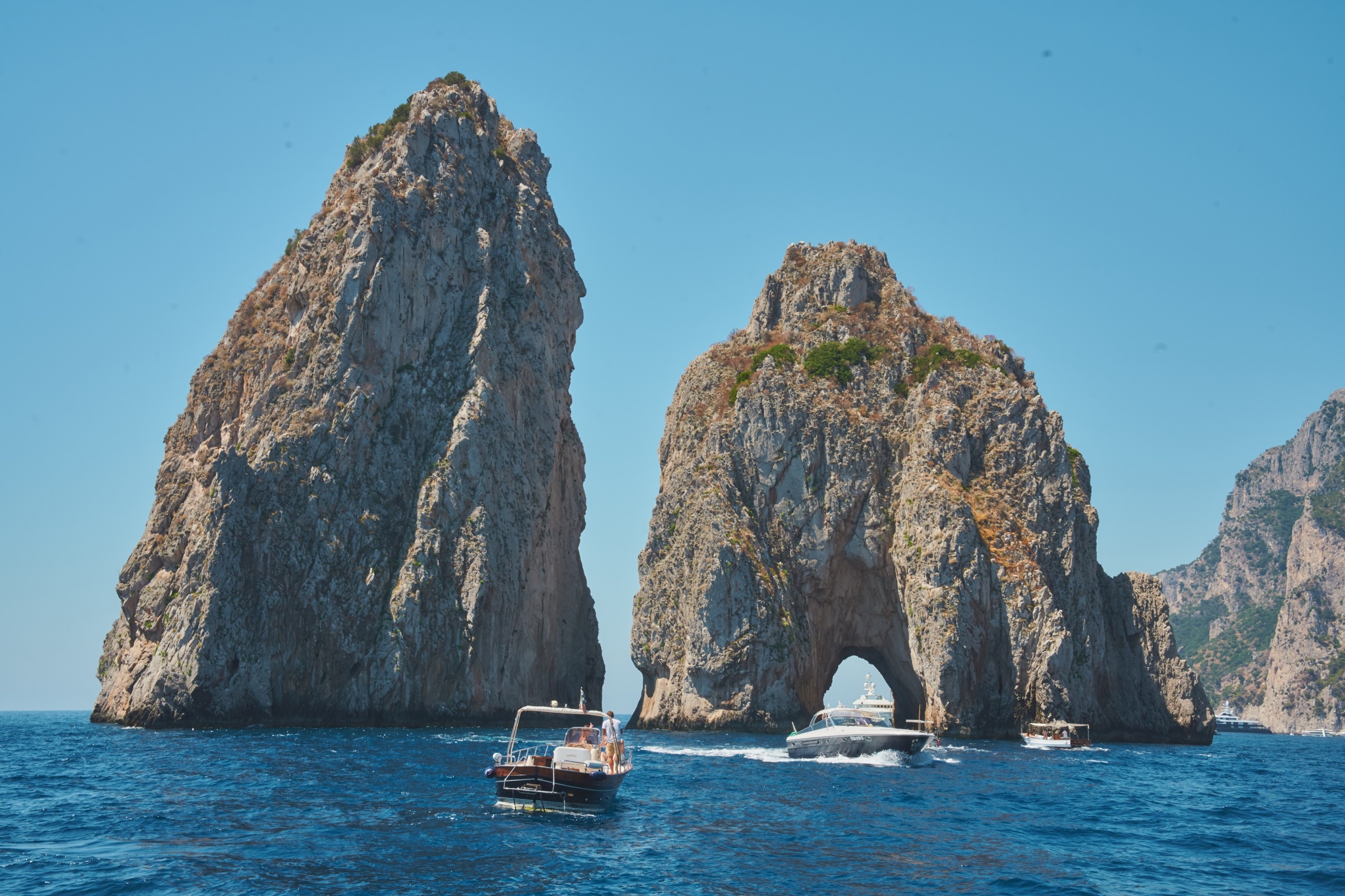 Classic Amalfi boat cruising with dramatic coastline and cliffs behind