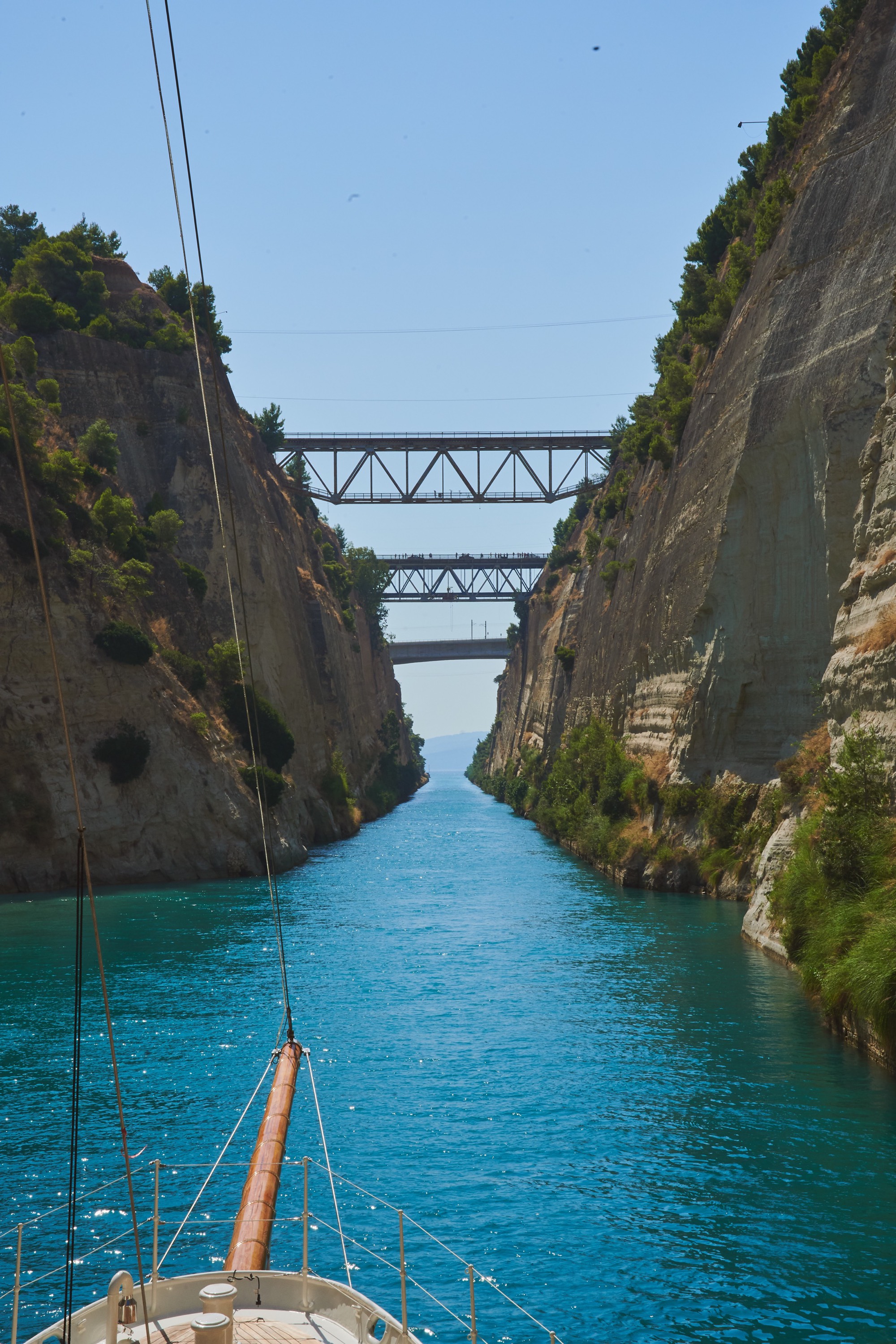 Corinth Canal portrait, steel bridges spanning the narrow passage, vivid blue water